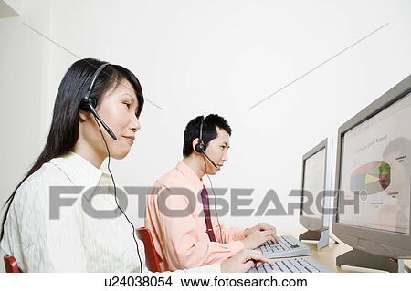 Picture - Two customer service representatives working on a computer. Fotosearch