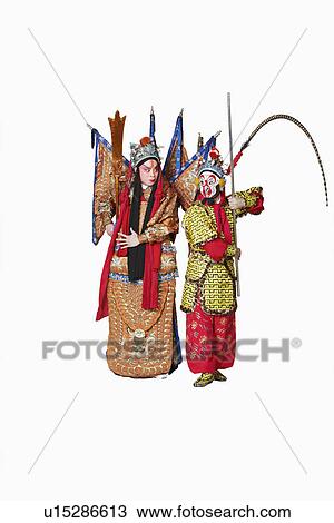 Stock Image - Two male Chinese opera performers gesturing with weapons. Fotosearch