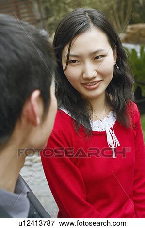 Stock Photo - Young couple looking at each other smiling. Fotosearch