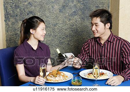 Stock Photography - Young couple sitting at a table in a restaurant. Fotosearch