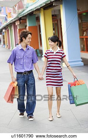 Stock Image - Young couple walking with shopping bags. Fotosearch