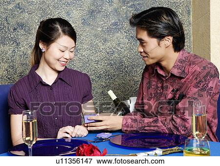Stock Photo - Young man giving a gift to a young woman in a restaurant. Fotosearch
