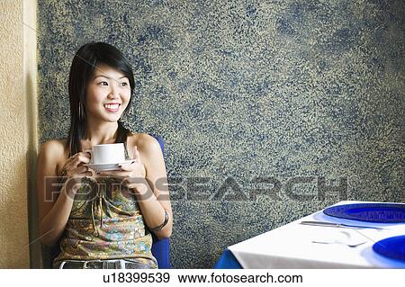 Young woman drinking a cup of coffee in a restaurant View Large Photo Image Stock Photo - Young woman drinking a cup of coffee in a restaurant. Fotosearch