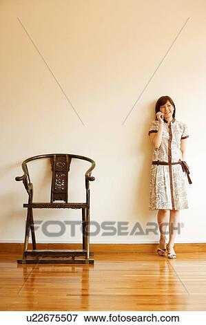 Young woman leaning against a wall and talking on a mobile phone View Large Photo Image Stock Photo - Young woman leaning against a wall and talking on a mobile phone. Fotosearch