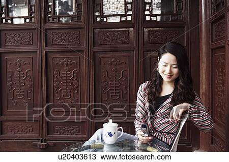 Young woman operating a mobile phone smiling View Large Photo Image Stock Image - Young woman operating a mobile phone smiling. Fotosearch
