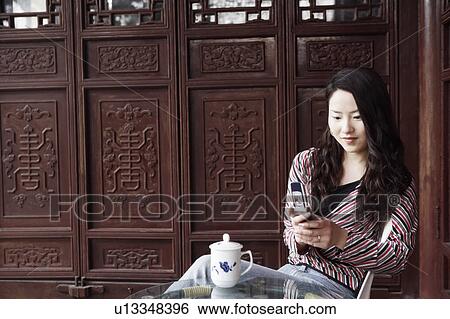Young woman operating a mobile phone smiling View Large Photo Image Stock Photograph - Young woman operating a mobile phone smiling. Fotosearch