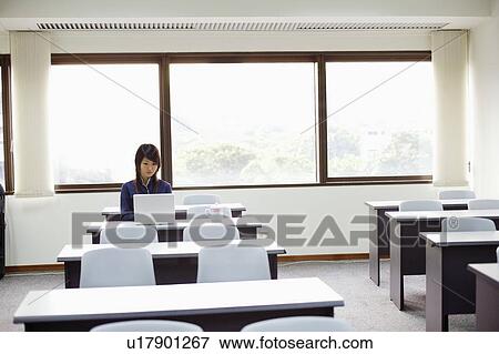 Young woman sitting and using a laptop View Large Photo Image Stock Photo - Young woman sitting and using a laptop. Fotosearch