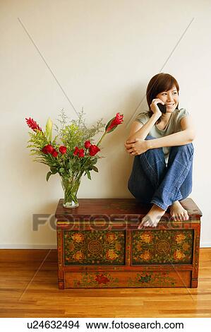 Young woman sitting on the table and talking on a mobile phone View Large Photo Image Picture - Young woman sitting on the table and talking on a mobile phone. Fotosearch
