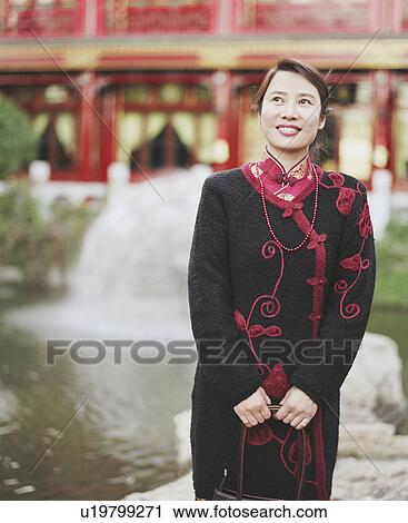 Stock Image - Young woman standing and looking up. Fotosearch