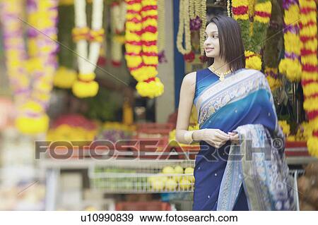 Stock Photo - Young woman standing in front of a garland shop. Fotosearch
