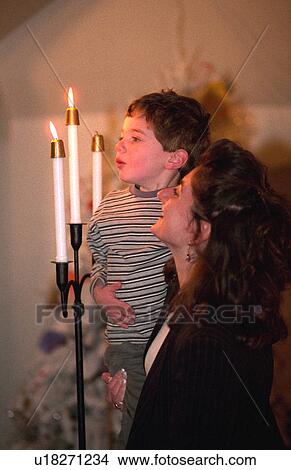 Picture - Mother age 32 helping son 4 blow out candles after cousins baptism. Fotosearch