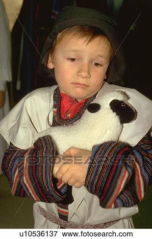 Stock Photo - Young shepherd age 7 hugging his lamb at Christmas pageant. Fotosearch