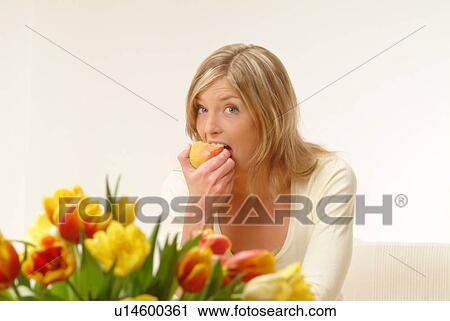 Woman eating apple, flowers in foreground View Large Photo Image Stock Image - Woman eating apple, flowers in foreground. Fotosearch