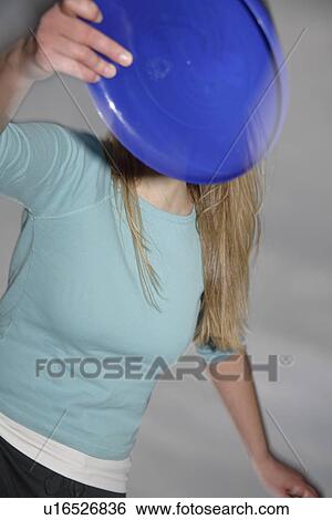 Stock Photograph - Woman playing with a frisbee, throwing and catching, in front of dark clouds. Fotosearch
