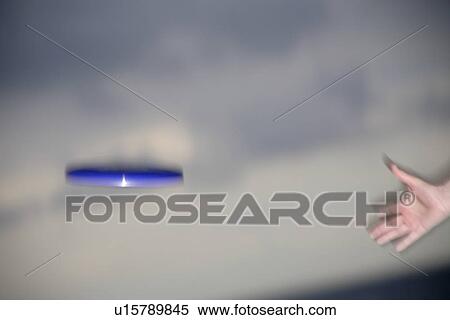 Stock Photography - Woman playing with a frisbee, throwing and catching, in front of dark clouds. Fotosearch