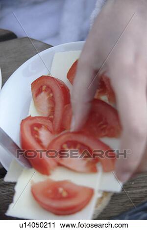 Stock Image - Woman preparing bread with cheese, tomato and basil. Fotosearch