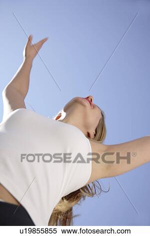 Woman stretching out arms in front of blue sky, low angle view View Large Photo Image Stock Photography - Woman stretching out arms in front of blue sky, low angle view. Fotosearch