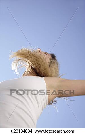 Young blond woman dancing, jumping and cheering at the beach, worm's eye view View Large Photo Image Picture - Young blond woman dancing, jumping and cheering at the beach, worm's eye view. Fotosearch