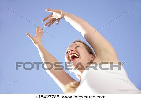 Young blond woman dancing, jumping and cheering at the beach, worm's eye view View Large Photo Image Stock Photography - Young blond woman dancing, jumping and cheering at the beach, worm's eye view. Fotosearch