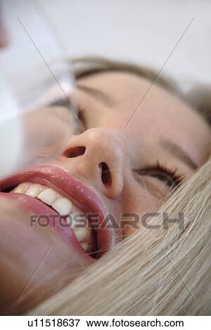 Stock Photo - Young blond woman drinking milk from a glass, milksop, close up. Fotosearch