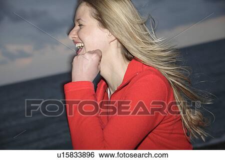 Stock Photograph - Young blond woman jogging at the beach, smiling. Fotosearch