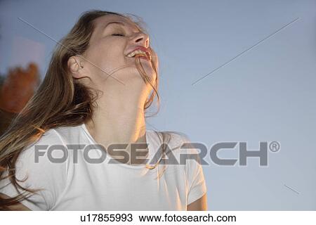 Stock Image - Young blond woman relaxing after jogging at the beach, close up. Fotosearch