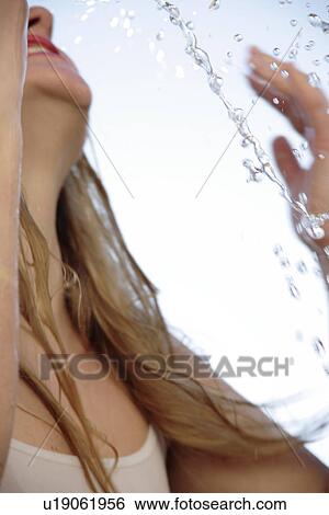 Stock Photograph - Young blond woman splashing water in her face, close up. Fotosearch