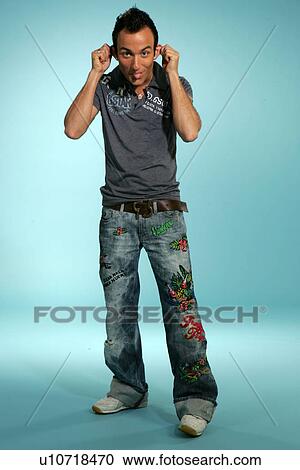 Stock Image - Young man in casual clothing, making a grimace, studio shot. Fotosearch