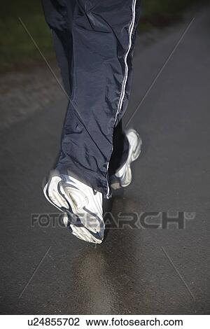 Stock Image - Young man jogging on a rainy day, legs close up. Fotosearch