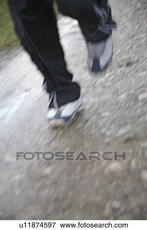Stock Photo - Young man jogging on a rainy day, legs close up. Fotosearch