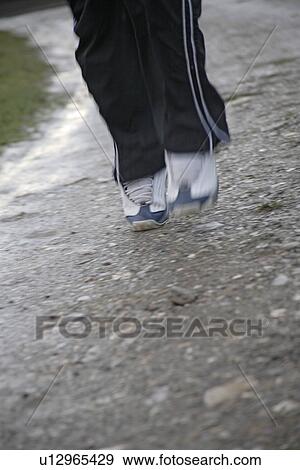Stock Photo - Young man jogging on a rainy day, legs close up. Fotosearch