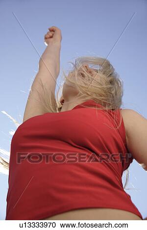 Young woman dancing and cheering with arms stretched out in front of blue sky, low angle view View Large Photo Image Stock Image - Young woman dancing and cheering with arms stretched out in front of blue sky, low angle view. Fotosearch