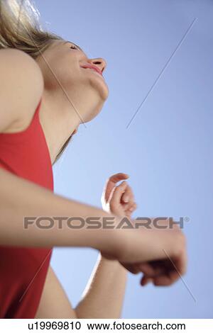 Young woman dancing and cheering with arms stretched out in front of blue sky, low angle view View Large Photo Image Stock Image - Young woman dancing and cheering with arms stretched out in front of blue sky, low angle view. Fotosearch