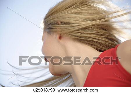 Stock Photo - Young woman in a happy mood in front of blue sky, view from below. Fotosearch