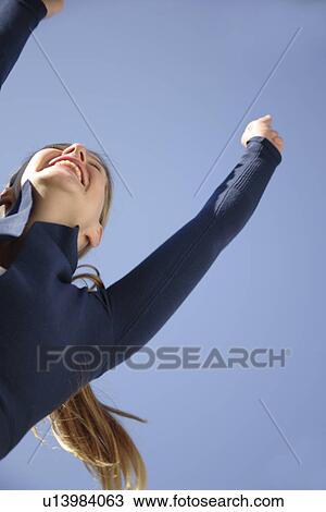 Young woman jumping happily in front of blue sky, view from below View Large Photo Image Stock Image - Young woman jumping happily in front of blue sky, view from below. Fotosearch