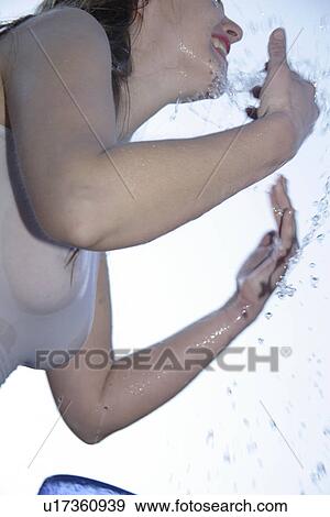 Young woman refreshing herself by splashing water all over her body, low angle view, close up View Large Photo Image Stock Photo - Young woman refreshing herself by splashing water all over her body, low angle view, close up. Fotosearch