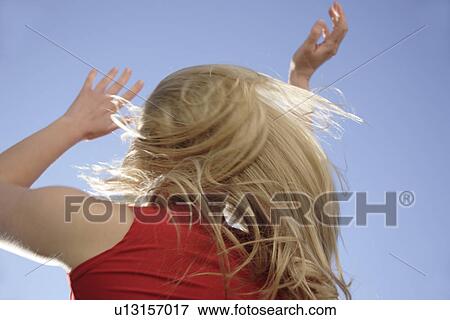 Young woman throwing her long blond hair in front of blue sky, low angle view View Large Photo Image Stock Photo - Young woman throwing her long blond hair in front of blue sky, low angle view. Fotosearch