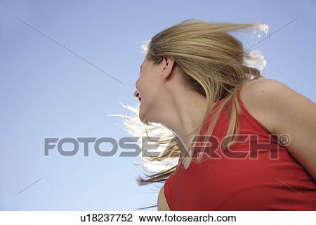 Young woman tossing her long blond hair in front of blue sky, view from below View Large Photo Image Stock Image - Young woman tossing her long blond hair in front of blue sky, view from below. Fotosearch