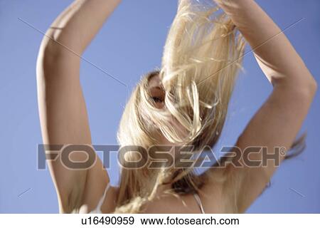 Young woman tossing her long blond hair in front of blue sky, view from below View Large Photo Image Stock Photo - Young woman tossing her long blond hair in front of blue sky, view from below. Fotosearch