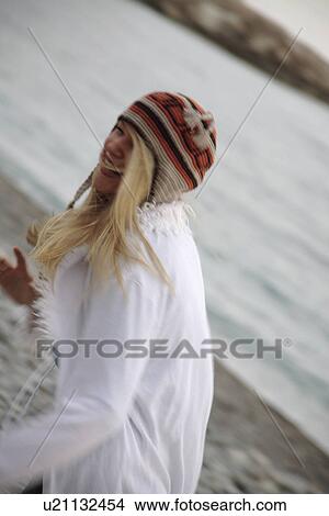 Young woman wearing knitted cap, running and laughing at the beach, close up View Large Photo Image Picture - Young woman wearing knitted cap, running and laughing at the beach, close up. Fotosearch