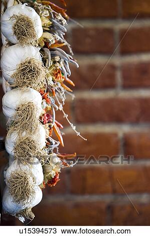 Stock Image - Detail of garlic and peppers against brick wall.. Fotosearch