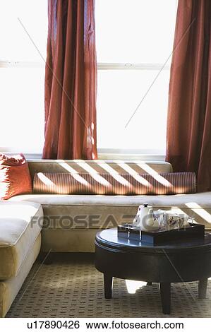 Stock Photograph - Sunlit Sofa in Room with Red Accents. Fotosearch