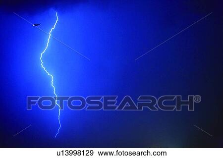 Stock Photo - Lightning bolt, Airplane flying in bad weather. Fotosearch