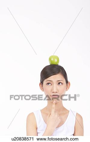 Stock Image - Portrait of Natural Young girl with an Apple on Her Head. Fotosearch