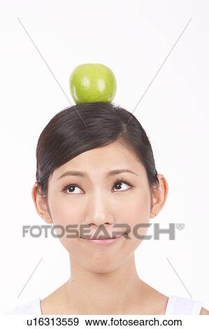 Stock Photo - Portrait of Natural Young girl with an Apple on Her Head. Fotosearch