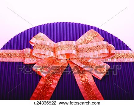 Stock Image - Round shaped box with golden bow, Close-up. Fotosearch