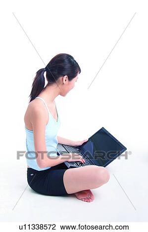 Young woman sitting and using notebook, crossed-legged View Large Photo Image Stock Image - Young woman sitting and using notebook, crossed-legged. Fotosearch