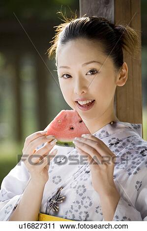 Stock Image - Yukata woman who eats a watermelon. Fotosearch