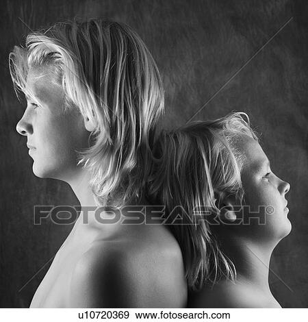Stock Photo - Adolescent and teen brothers standing back to back.. Fotosearch