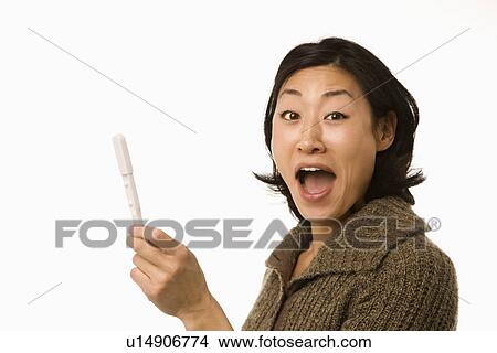Asian mid adult woman holding up pregnancy test looking excited. View Large Photo Image Picture - Asian mid adult woman holding up pregnancy test looking excited.. Fotosearch